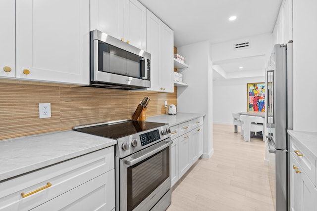 kitchen featuring stainless steel appliances, tasteful backsplash, light stone countertops, and white cabinets