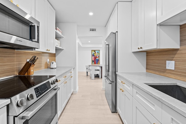 kitchen featuring white cabinetry, appliances with stainless steel finishes, light stone counters, and light hardwood / wood-style floors