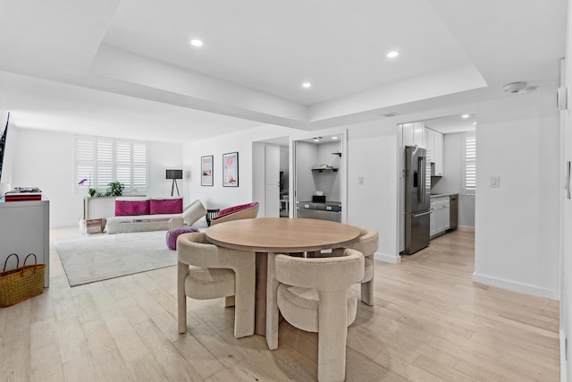 dining room featuring a tray ceiling and light hardwood / wood-style flooring