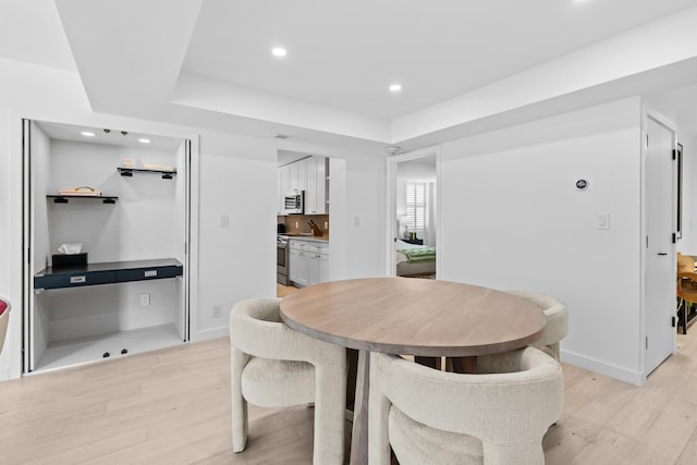 dining space featuring a raised ceiling and light hardwood / wood-style floors