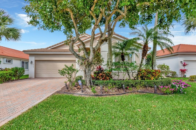 view of front of home with a garage, decorative driveway, a front yard, and stucco siding