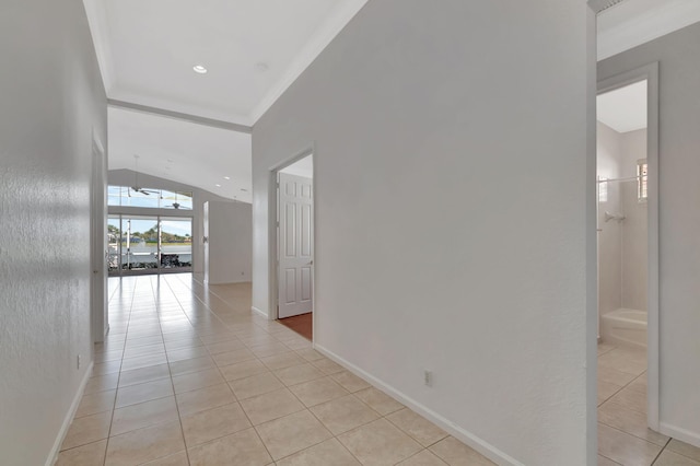 hallway with ornamental molding, vaulted ceiling, baseboards, and light tile patterned floors