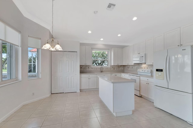 kitchen featuring white appliances, decorative backsplash, light countertops, and a sink