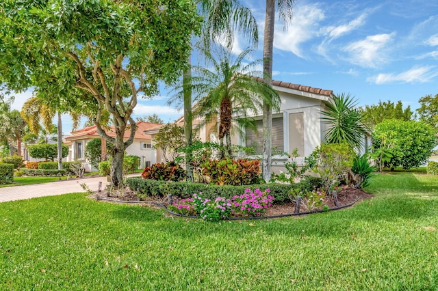 exterior space with decorative driveway, a tile roof, a lawn, and stucco siding