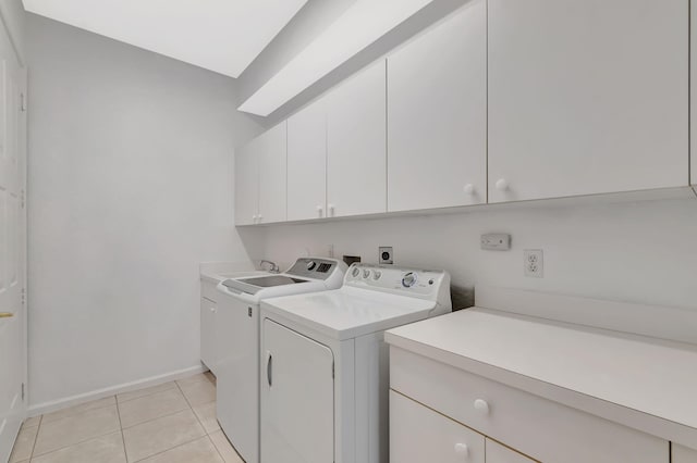 washroom with cabinet space, washing machine and dryer, light tile patterned floors, and baseboards