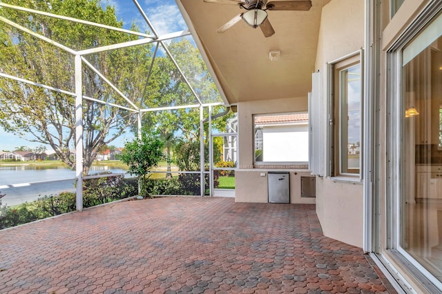 view of patio featuring a water view, a lanai, and a ceiling fan