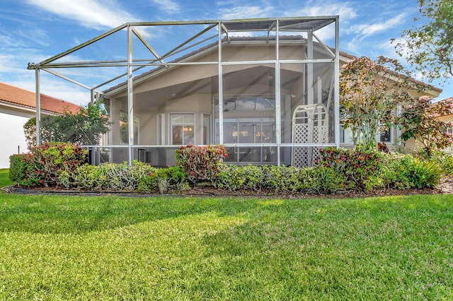 back of house featuring a yard, glass enclosure, and stucco siding