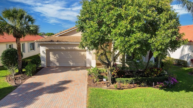 view of front of home with decorative driveway, a tile roof, stucco siding, an attached garage, and a front lawn