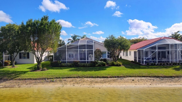 rear view of property featuring a lanai, a lawn, a tiled roof, and stucco siding