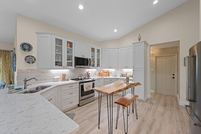 kitchen with lofted ceiling, sink, white cabinets, and appliances with stainless steel finishes