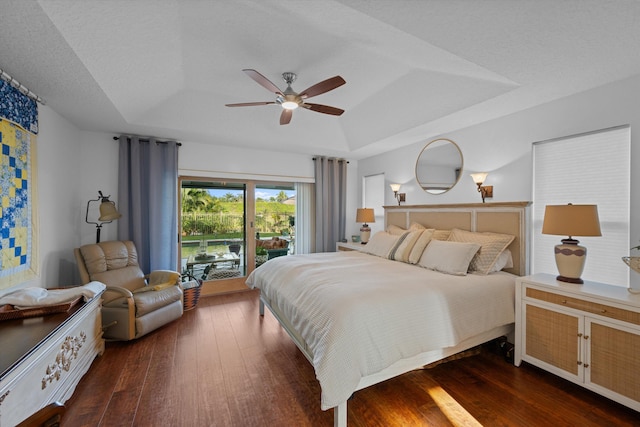 bedroom featuring dark hardwood / wood-style flooring, a tray ceiling, access to outside, and a textured ceiling