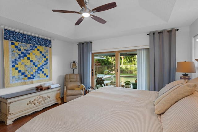 bedroom with hardwood / wood-style floors, access to outside, a raised ceiling, and ceiling fan