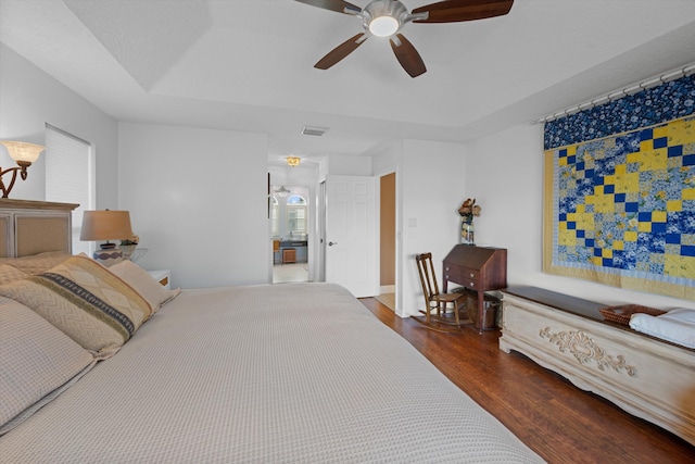 bedroom featuring ceiling fan, a tray ceiling, and dark hardwood / wood-style flooring