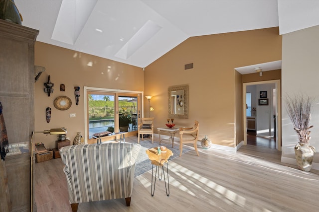 living room featuring high vaulted ceiling and light hardwood / wood-style flooring