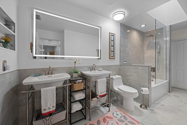 full bathroom with tiled shower / bath combo, sink, tile walls, and toilet