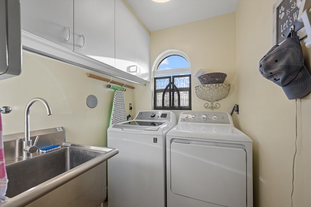 clothes washing area with cabinets, washer and clothes dryer, and sink