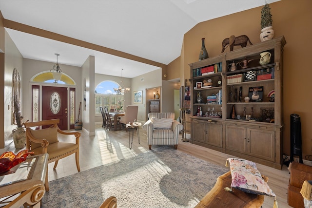 living room featuring an inviting chandelier, vaulted ceiling, and light hardwood / wood-style floors