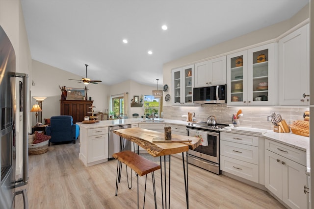 kitchen featuring lofted ceiling, sink, white cabinetry, stainless steel appliances, and decorative backsplash