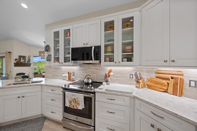 kitchen featuring white cabinetry, sink, backsplash, light stone counters, and stainless steel appliances