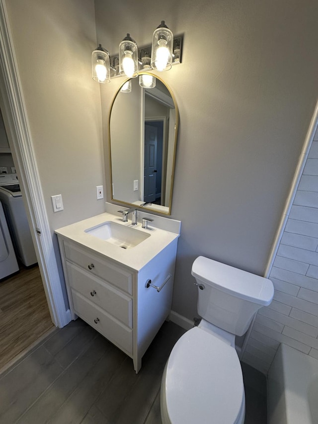 bathroom featuring vanity, hardwood / wood-style floors, washer / dryer, and toilet