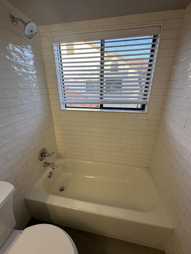 bathroom featuring tiled shower / bath combo and toilet