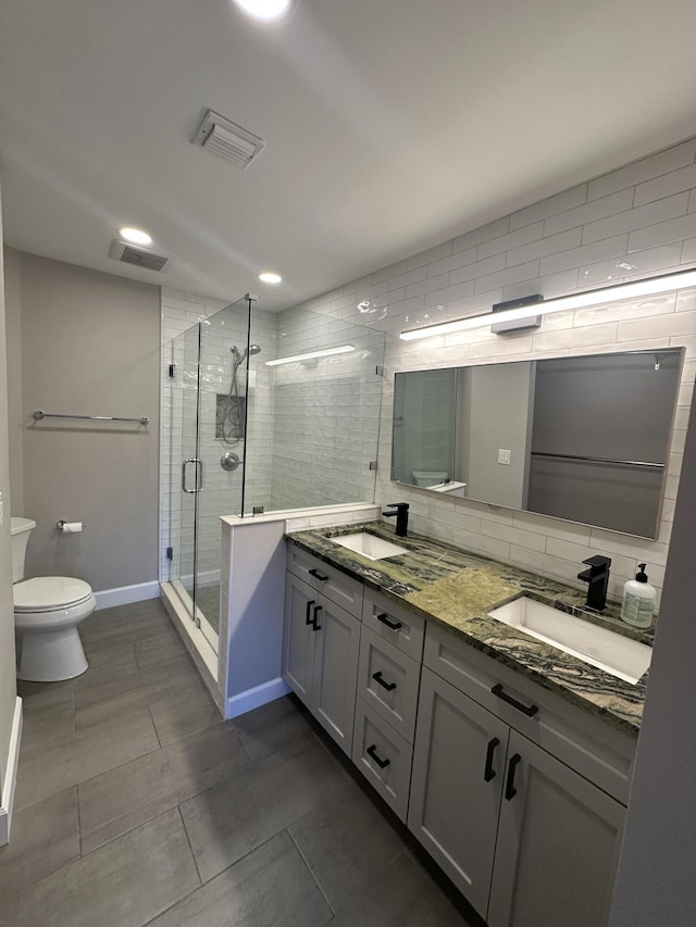 bathroom with tasteful backsplash, vanity, toilet, and a shower with door