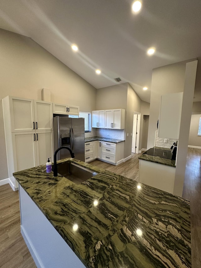 kitchen with white cabinetry, sink, dark stone countertops, stainless steel refrigerator with ice dispenser, and light hardwood / wood-style flooring