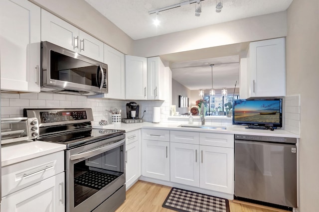 kitchen with stainless steel appliances, light countertops, a sink, and white cabinetry