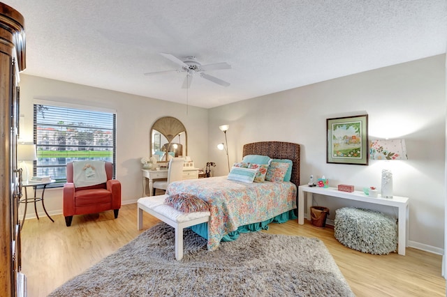 bedroom featuring a textured ceiling, ceiling fan, light wood finished floors, and baseboards