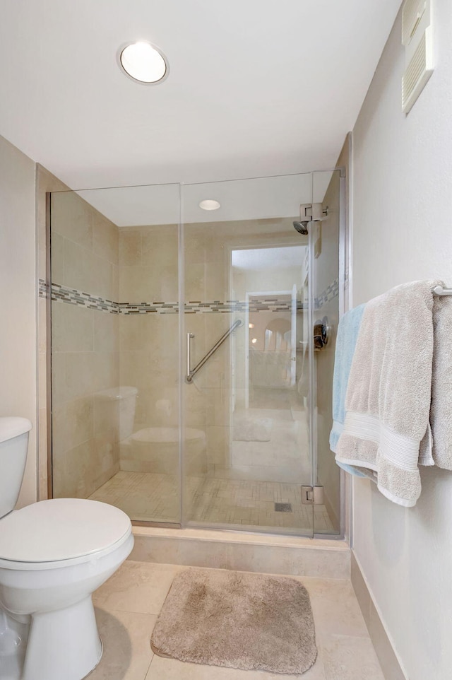 bathroom featuring a stall shower, toilet, and tile patterned floors