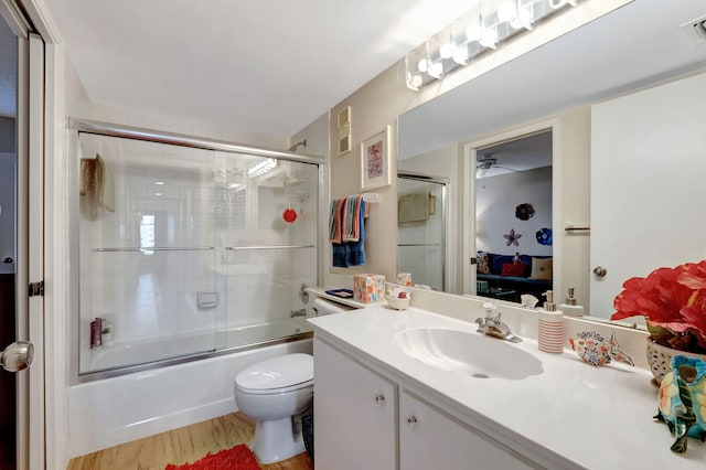 ensuite bathroom featuring toilet, enclosed tub / shower combo, connected bathroom, vanity, and wood finished floors