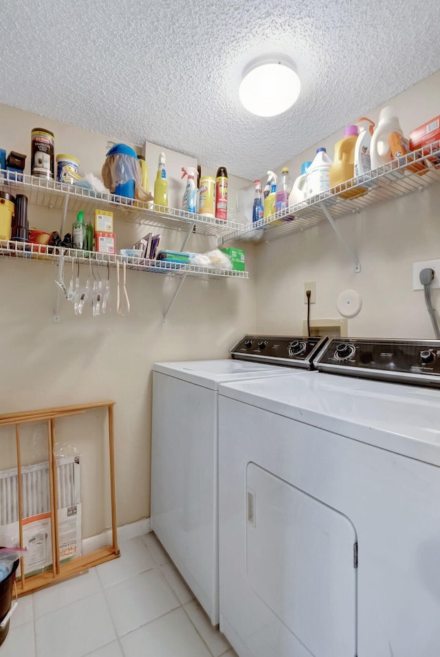 clothes washing area with a textured ceiling, laundry area, light tile patterned floors, and washing machine and dryer