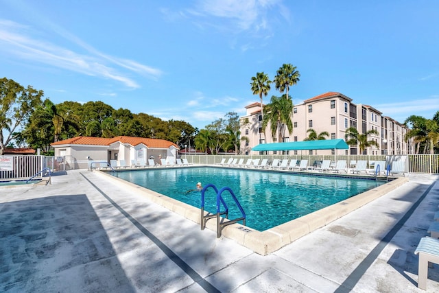 community pool featuring a patio, fence, and a residential view