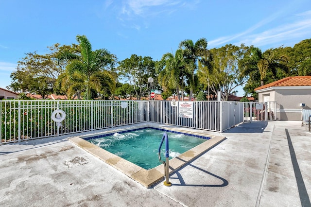 view of swimming pool featuring a hot tub and fence