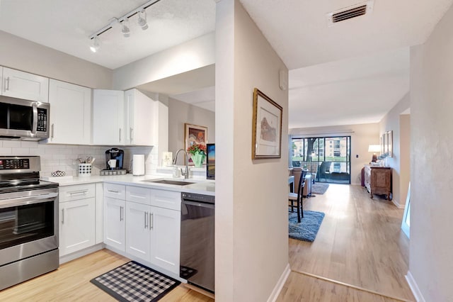 kitchen with stainless steel appliances, light countertops, visible vents, white cabinets, and a sink