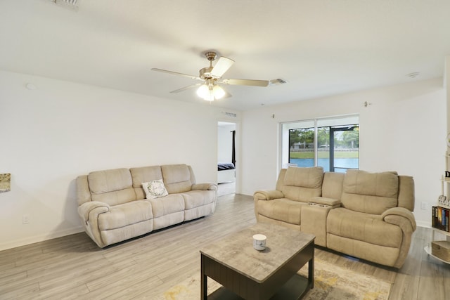 living area featuring baseboards, visible vents, ceiling fan, and light wood finished floors