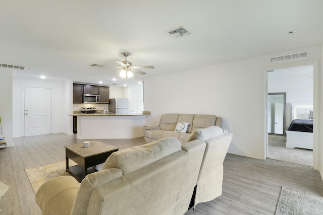 living area featuring a ceiling fan, visible vents, and light wood-style floors