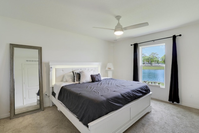 bedroom with a water view, ceiling fan, visible vents, and light colored carpet