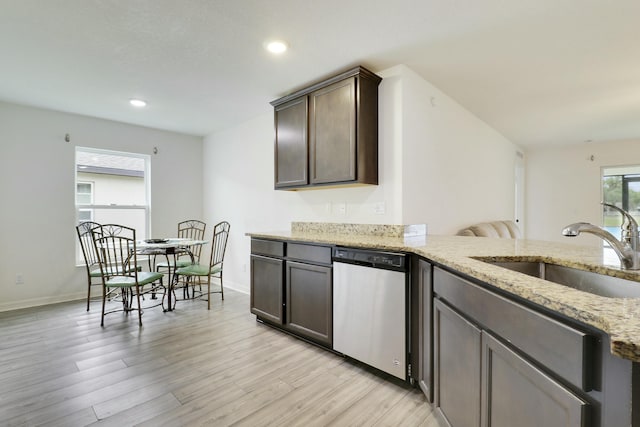 kitchen featuring light wood finished floors, light stone counters, dark brown cabinets, stainless steel dishwasher, and a sink