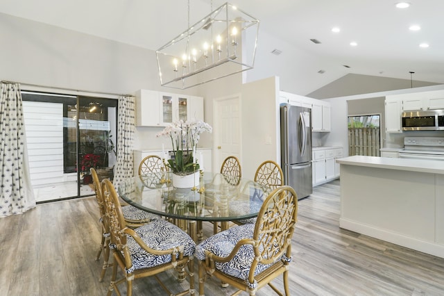 dining area with vaulted ceiling and light wood-type flooring