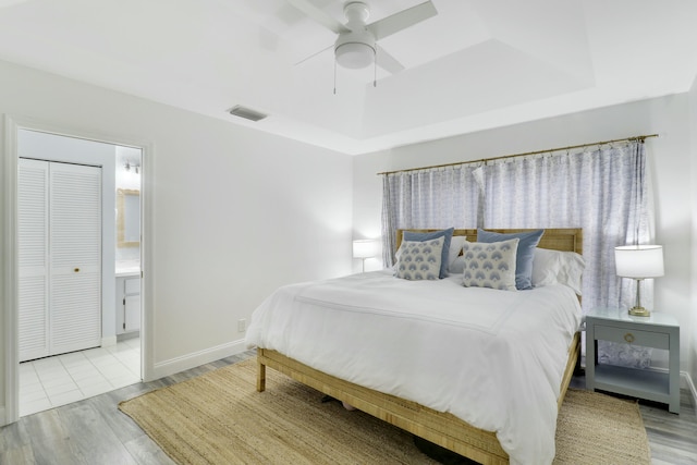 bedroom featuring ceiling fan, a tray ceiling, and light hardwood / wood-style floors