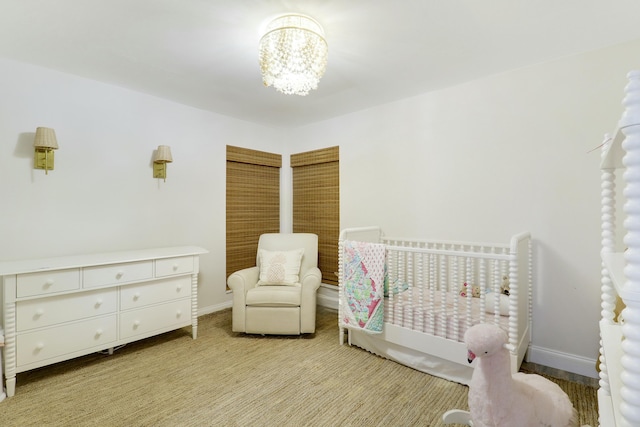 bedroom featuring a nursery area, light colored carpet, and a chandelier