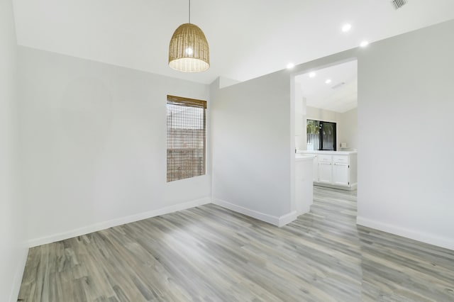 empty room featuring vaulted ceiling and light wood-type flooring