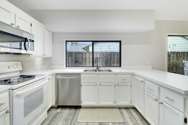 kitchen with stainless steel appliances, white cabinetry, sink, and kitchen peninsula