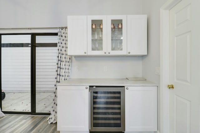 bar with white cabinetry, beverage cooler, and light wood-type flooring