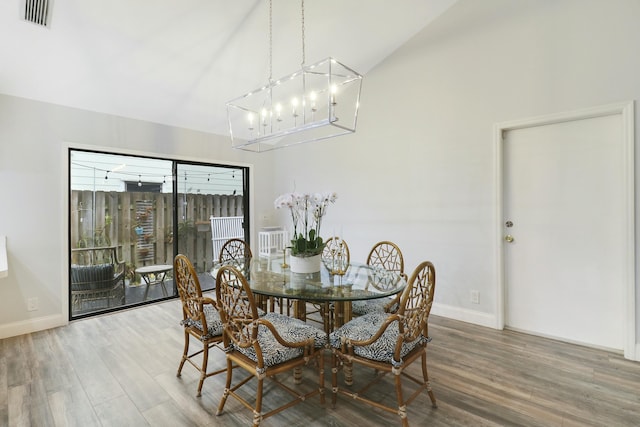 dining room featuring hardwood / wood-style flooring, vaulted ceiling, and a notable chandelier