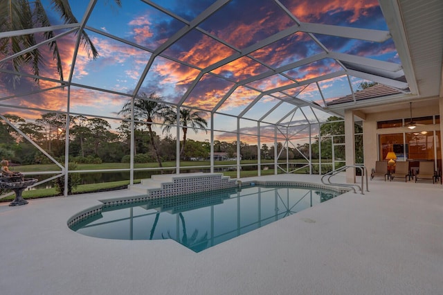 pool at dusk with a patio area and glass enclosure