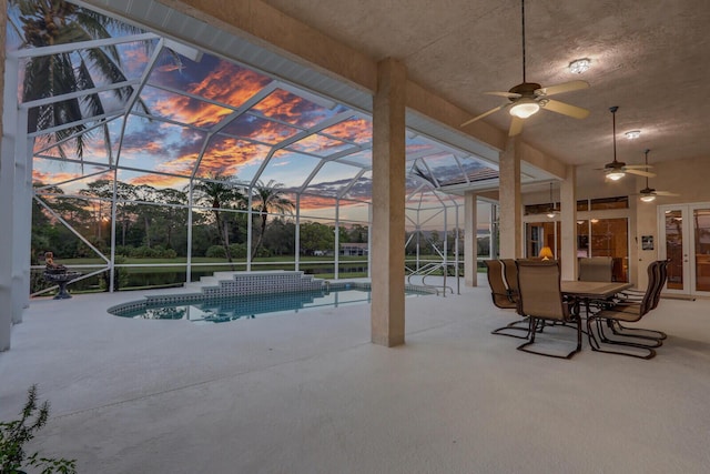 pool at dusk featuring french doors, ceiling fan, a lanai, and a patio area