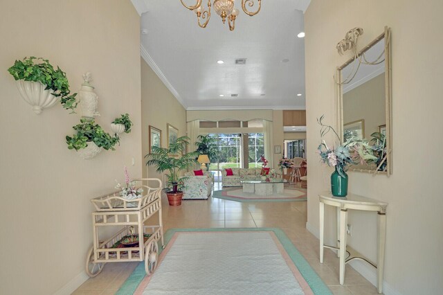 tiled entrance foyer with ornamental molding and a chandelier