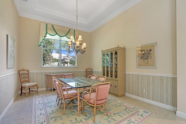 tiled dining room with a raised ceiling, crown molding, and an inviting chandelier